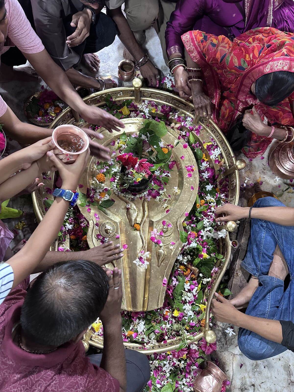 Devotees offering flowers and jal on the sacred Shivling