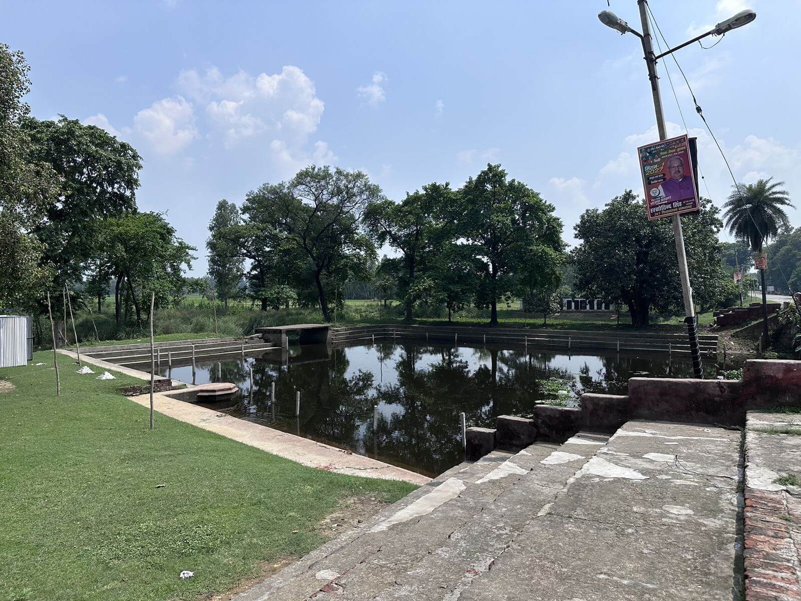 Rectangular holy pond with steps and trees at Mahadeva